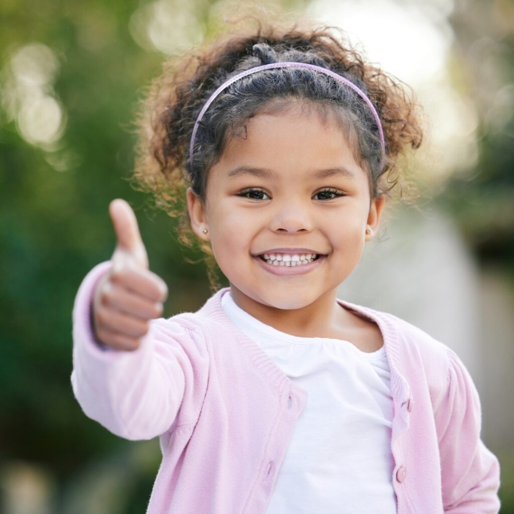 young girl holding thumbs up sign